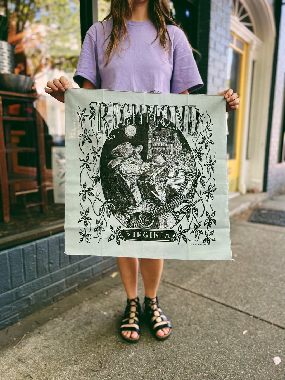 A woman holding up a Limited Edition Richmond Friends Bandana by The Wild Wander.