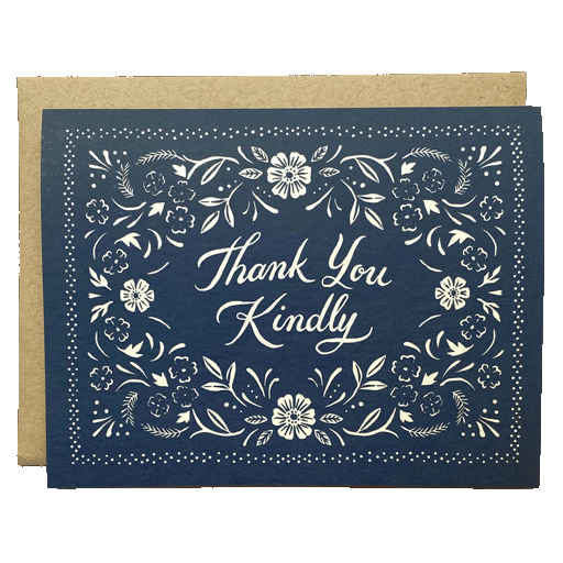 A navy blue thank you card with "Thank You Kindly" written in white script at the center, surrounded by white floral and leaf designs. Behind the card is a brown envelope.