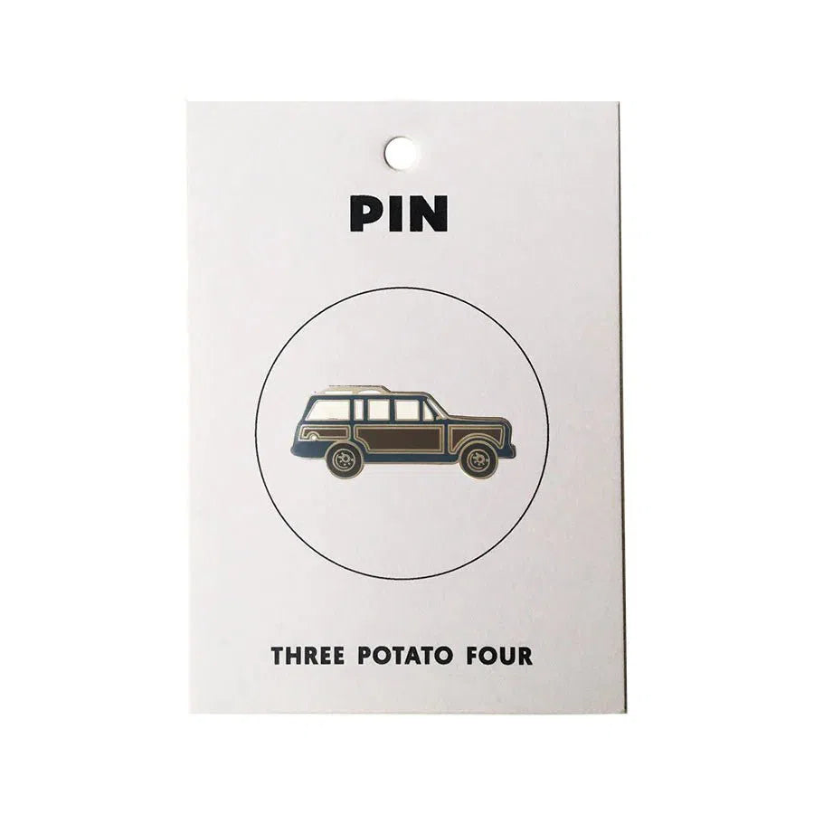 A Grand Wagoneer Enamel Pin with a brown and blue jeep on a white background by Three Potato Four.