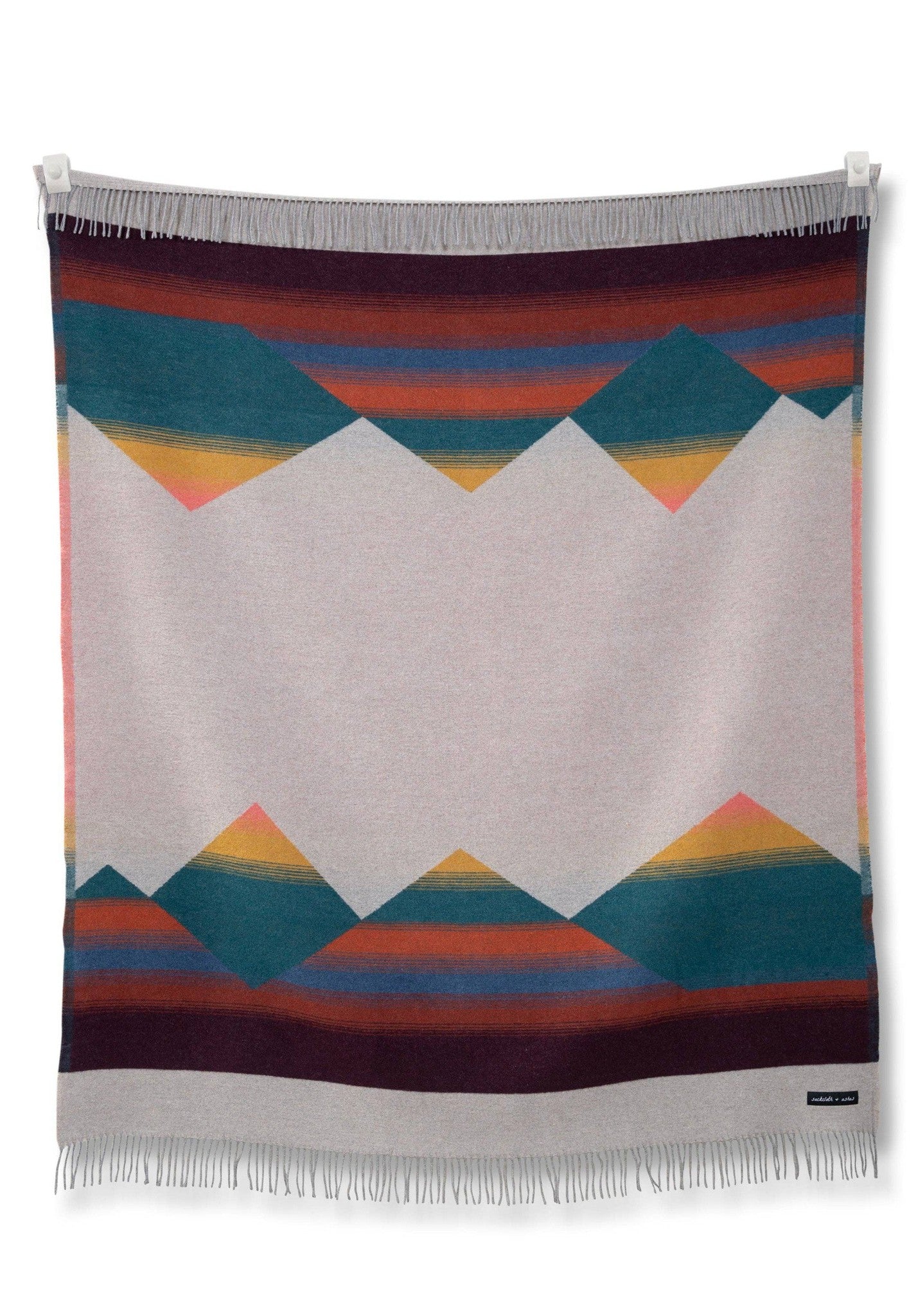 A colorful Mountain Tropic blanket hanging on a wall by Sackcloth & Ashes.