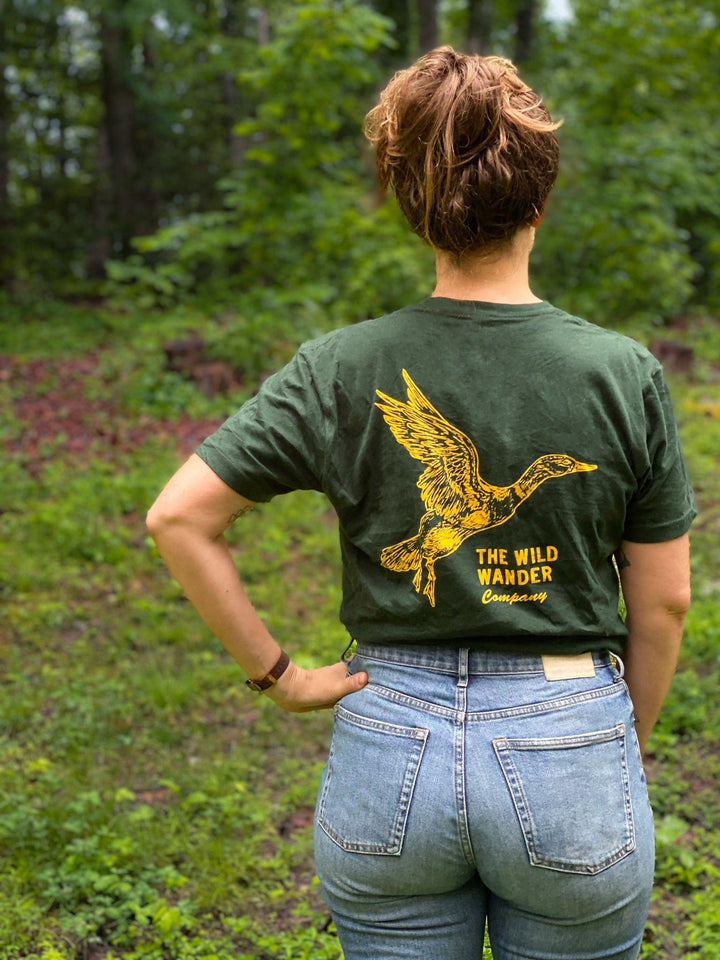 A woman wearing The Wild Wander Duck T-Shirt from The Wild Wander brand standing in the woods.